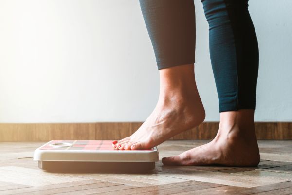 Woman stepping on a scale, medical weight loss management
