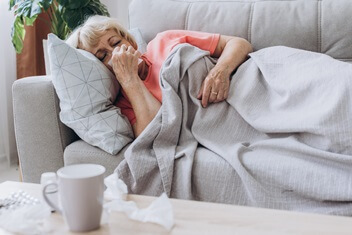 older woman on couch with cold and flu symptoms | flu treatment in Caldwell, Idaho