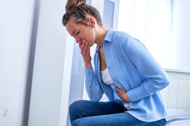 woman with nausea holding her stomach and mouth